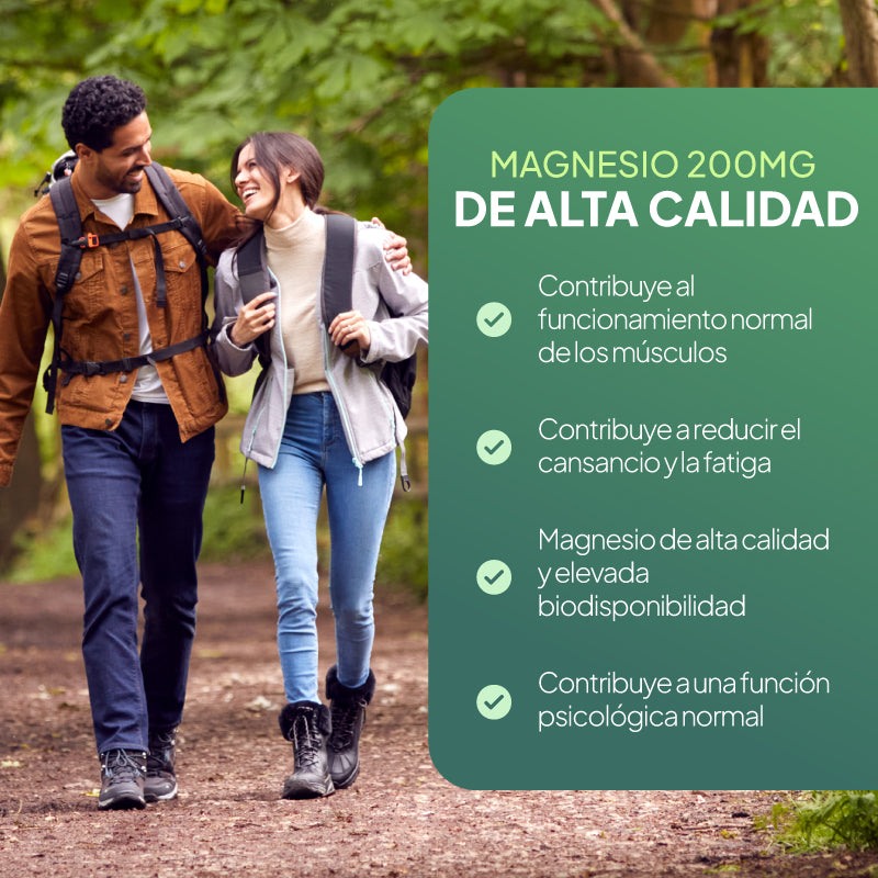 Un hombre y una mujer caminan cogidos del brazo por un sendero del bosque; a la derecha hay un gran cartel verde en el que se anuncian, en español, los beneficios del magnesio de 200 mg.